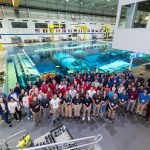 A large group standing in front of a pool posing for a group photo.