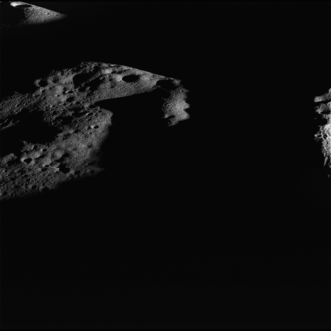 Darkness surrounds illuminated peaks near Shackleton crater (rim crest at right), seen in an image captured by the Lunar Reconnaissance Orbiter Cam...