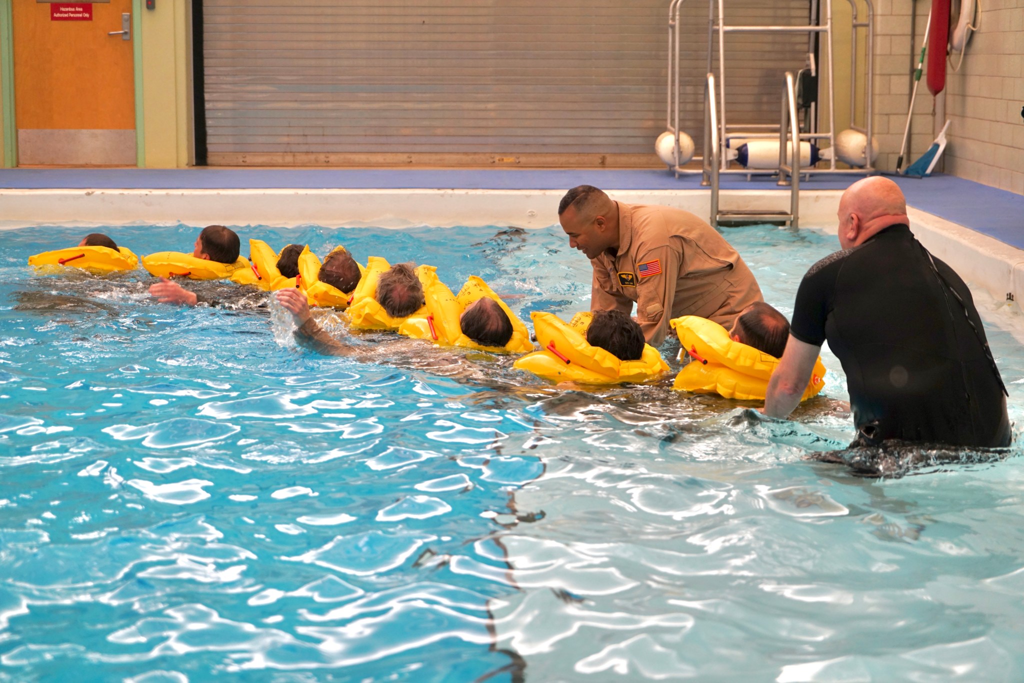 NASA research pilot David Zahn, standing, left, and Roger Storey, Federal Aviation Administration Aviation Physiology and post-crash survival instructor, lead pilots through group water survival training at the FAA Civil Aerospace Medical Institute.
