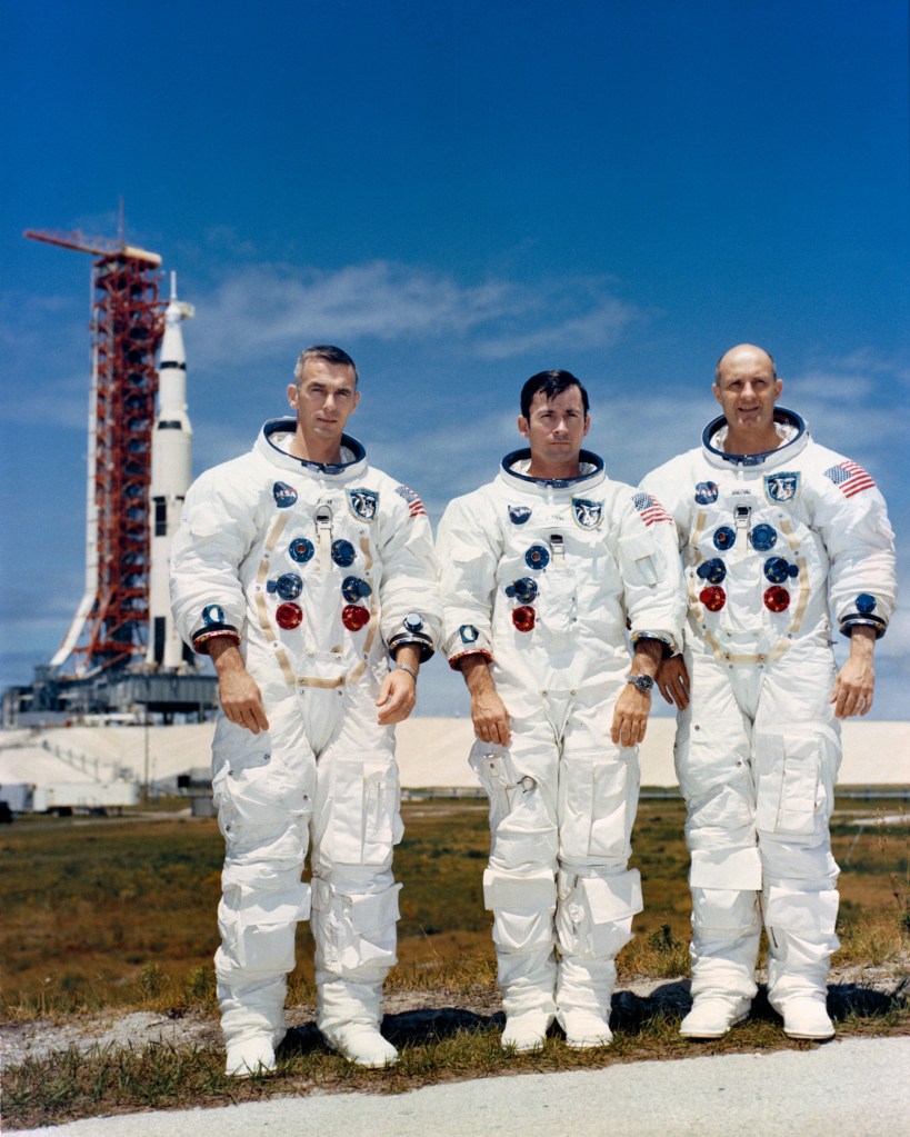 Cernan, left, Young, and Stafford pose in front of their Saturn V rocket
