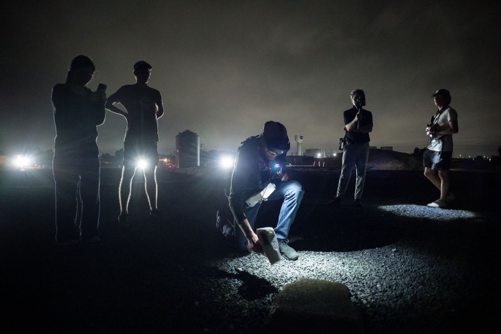 Five people stand outside at night time to test new technologies in a rock yard.